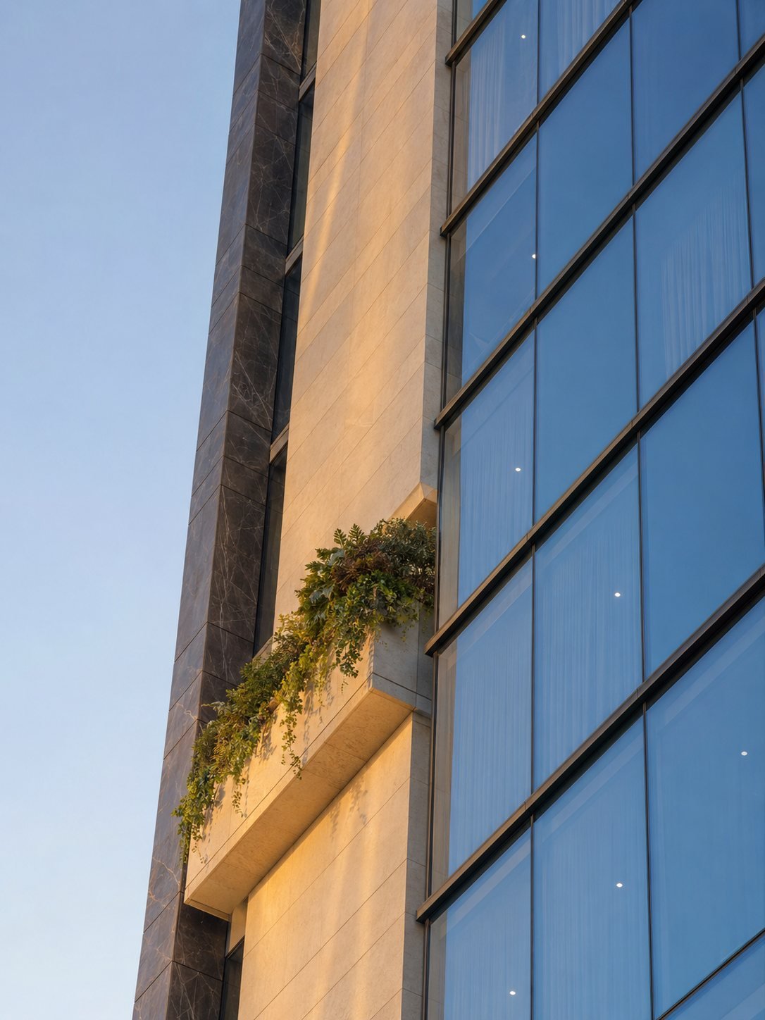 Concept render: facade detail with planted balcony where the glass curtain wall meets the limestone body